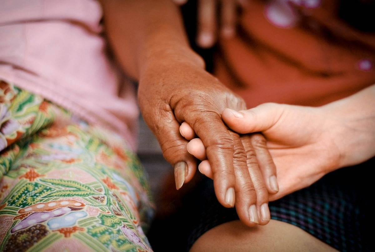 Two people holding hands, one wearing a brightly patterned dress.