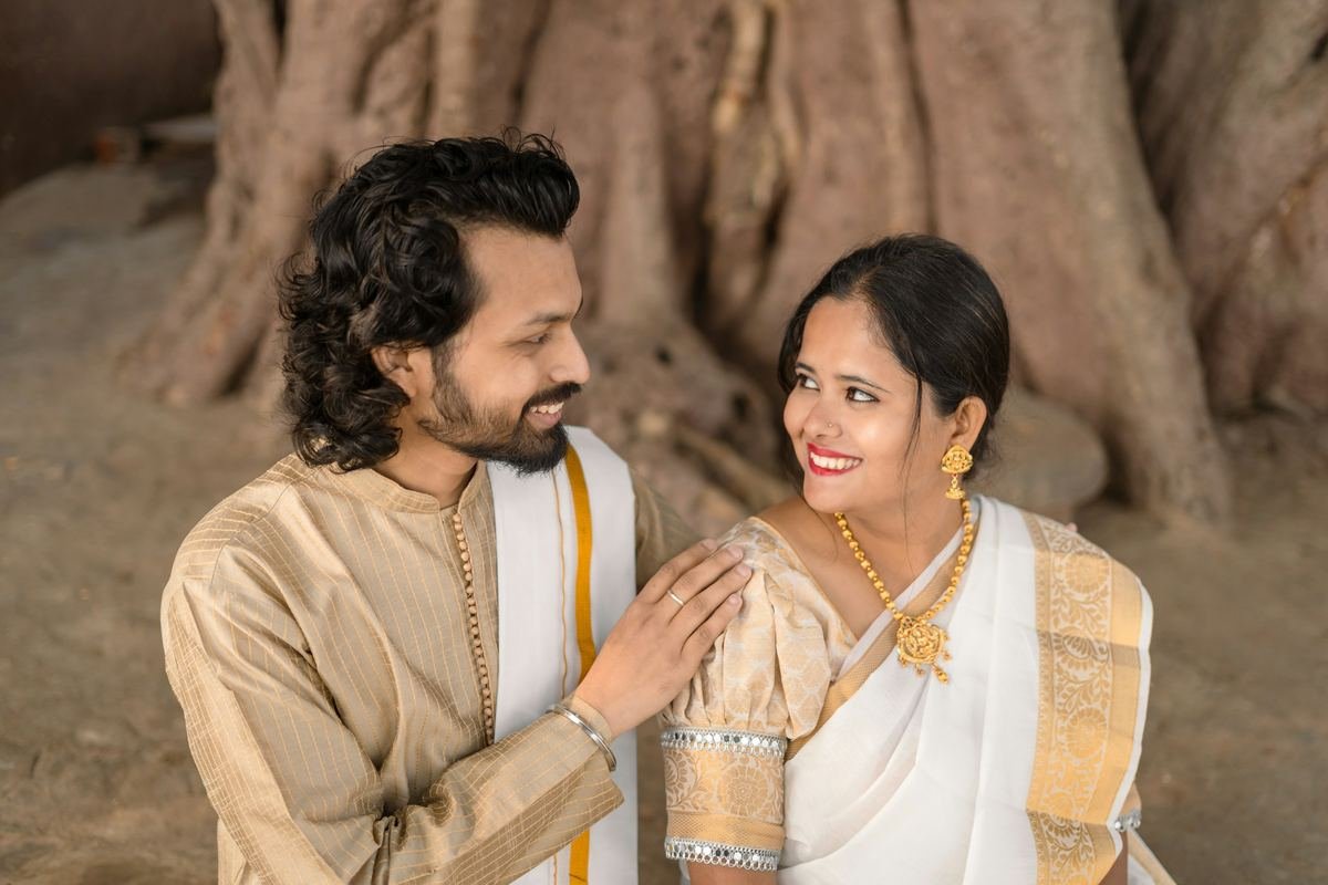 A couple in traditional clothes smiling at each other.