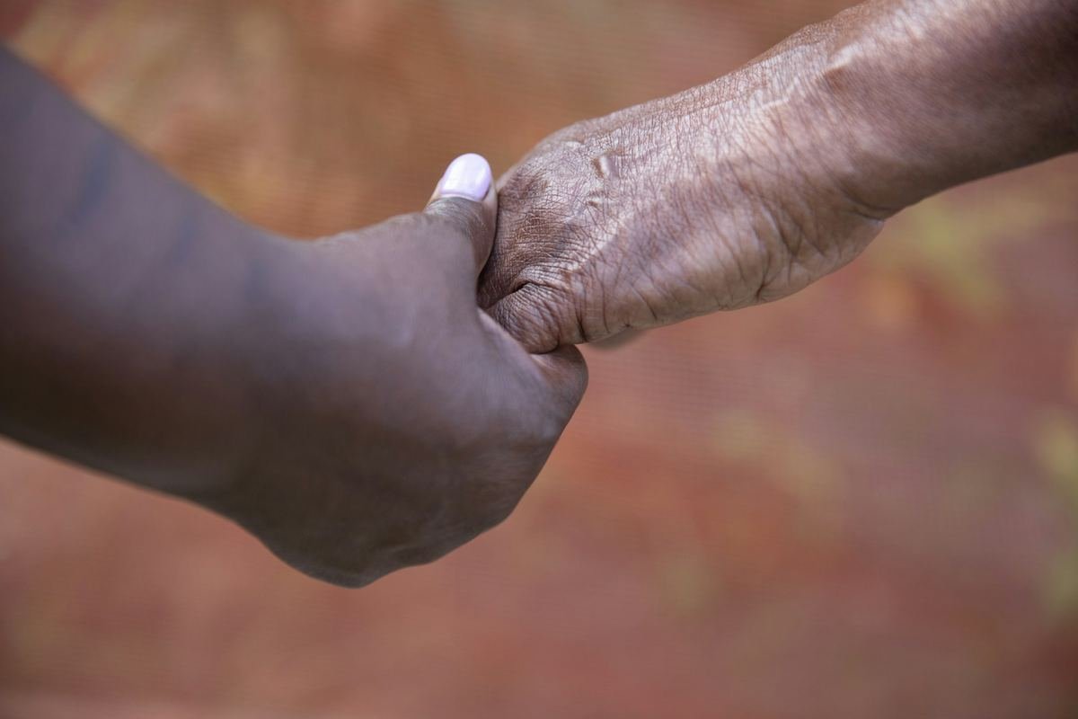 Two hands clasped together in warm light.
