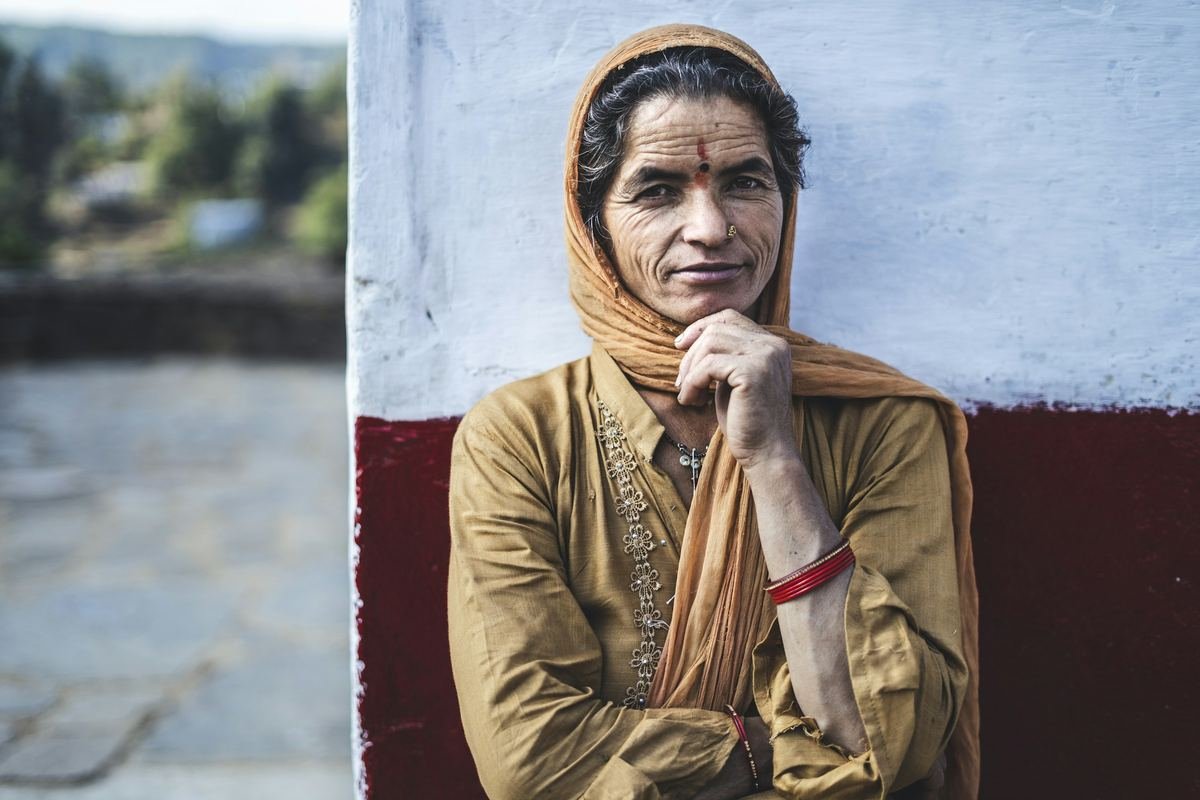A woman in a headscarf resting her chin on her hand.