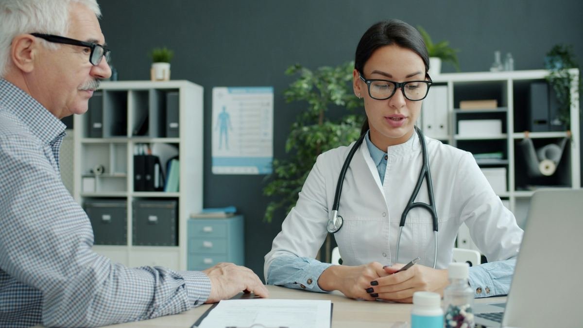 A doctor listening to an older patient during a consultation.