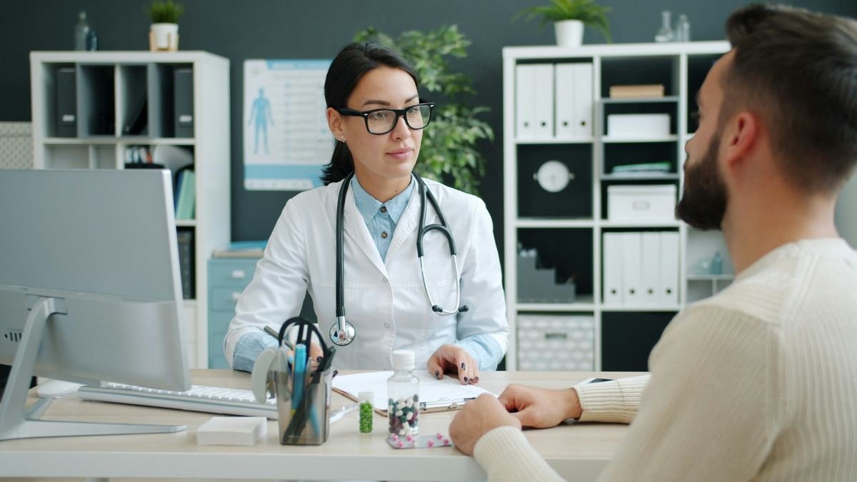 A doctor talking with a patient across a desk in a medical office.
