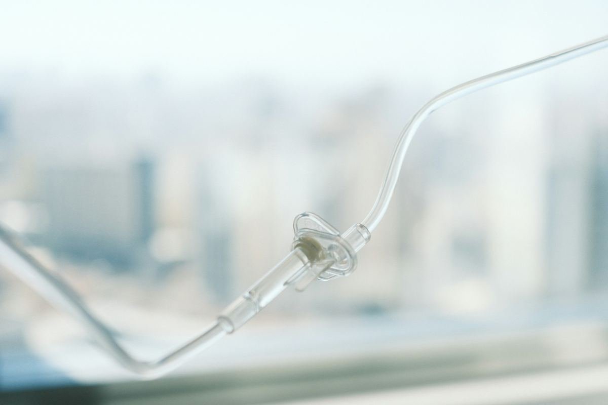 An intravenous drip line against a soft, blurred window.