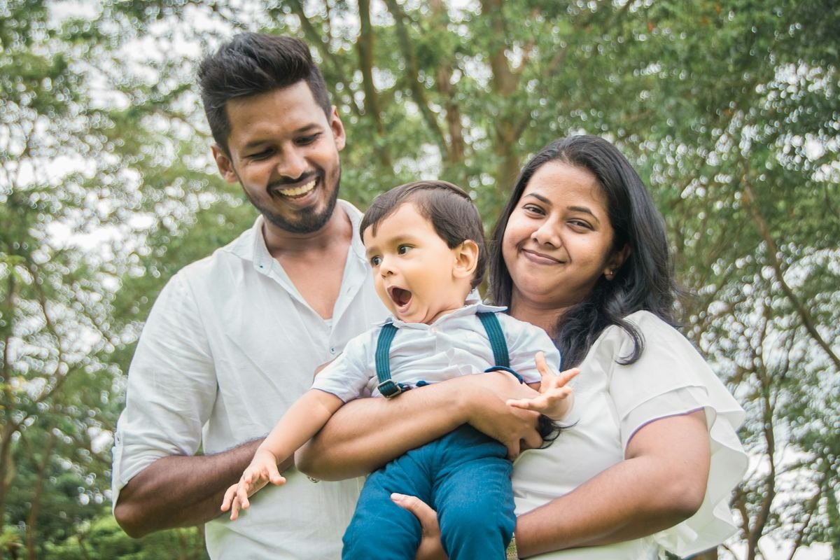 A young family smiling together outdoors.