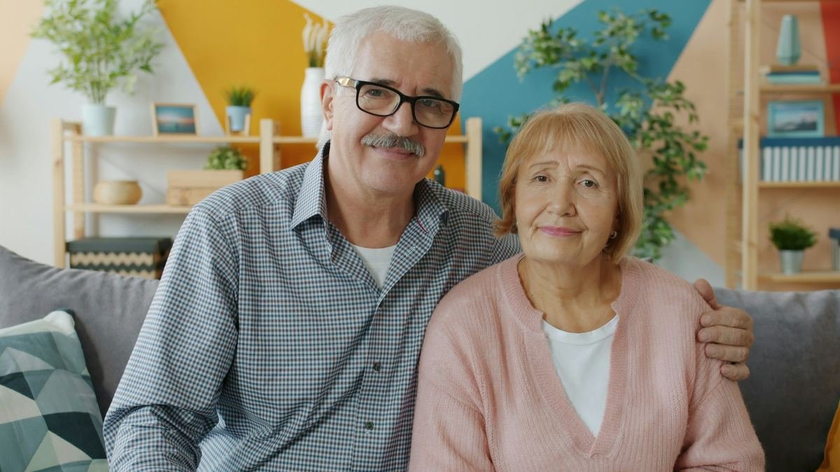 An older couple smiling together at home.