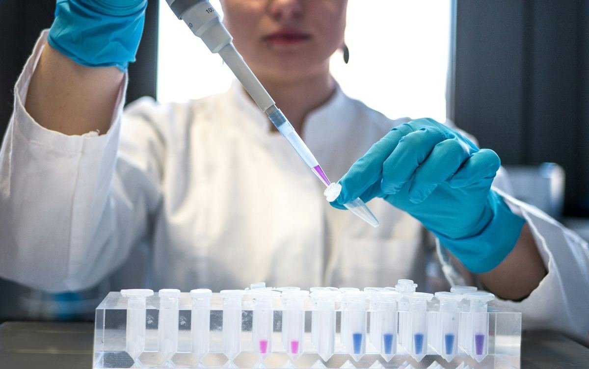 A scientist using a pipette over a row of sample tubes.