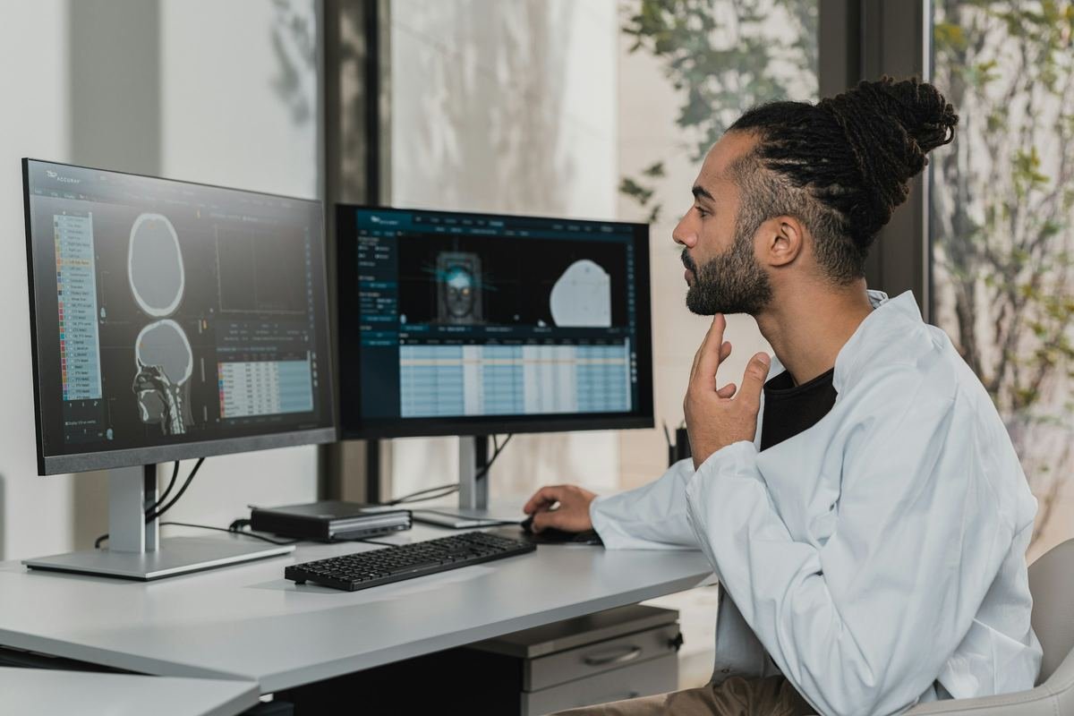 A clinician thinking while reviewing images on two screens.