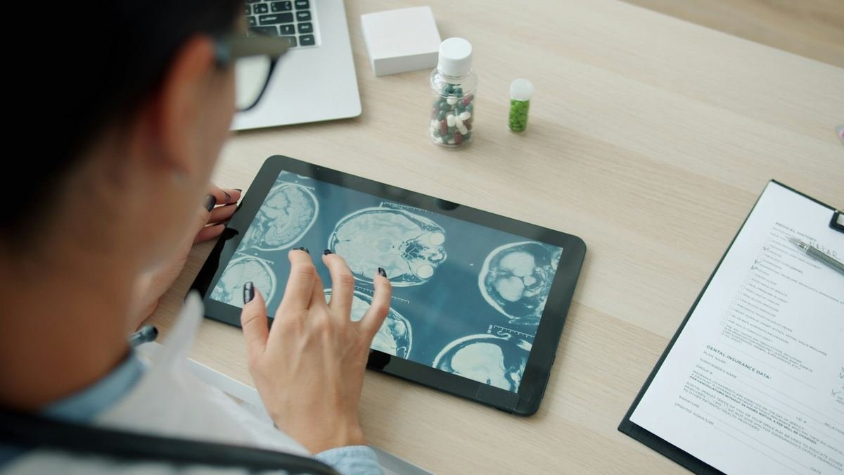 A clinician reviewing scan images on a tablet beside medicine bottles.