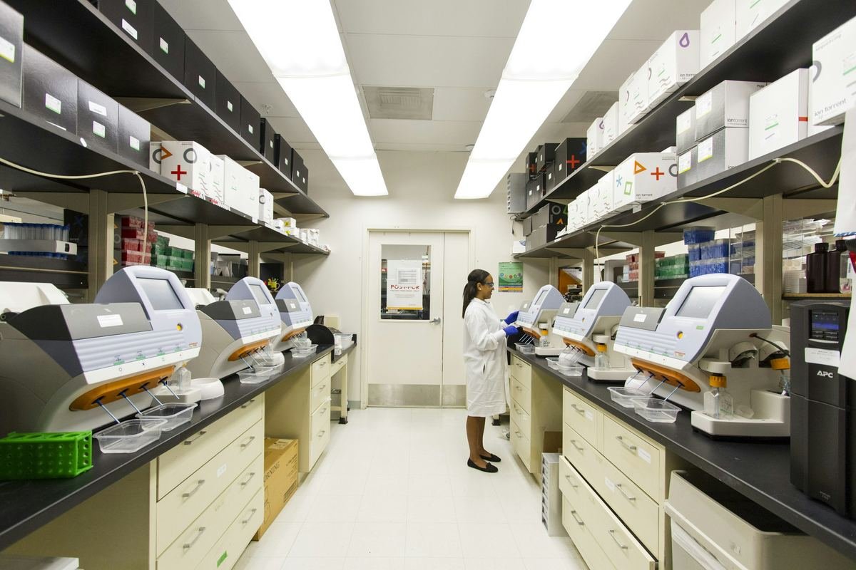 A technician working among genomic sequencing machines in a laboratory.